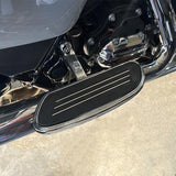 Black and chrome motorcycle footboard with engine detail on concrete floor