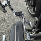 Close-up of motorcycle chrome brake pedal and footrest on asphalt road